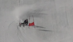 Skier going down a hill past a flag on course.